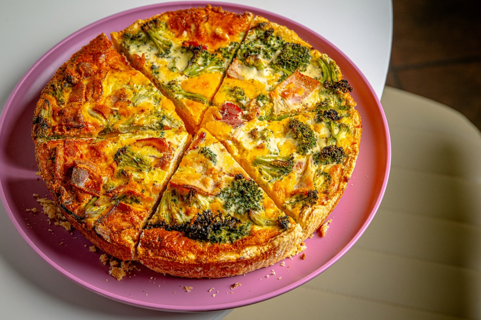 A whole golden quiche on a pink plate at Café Bliss