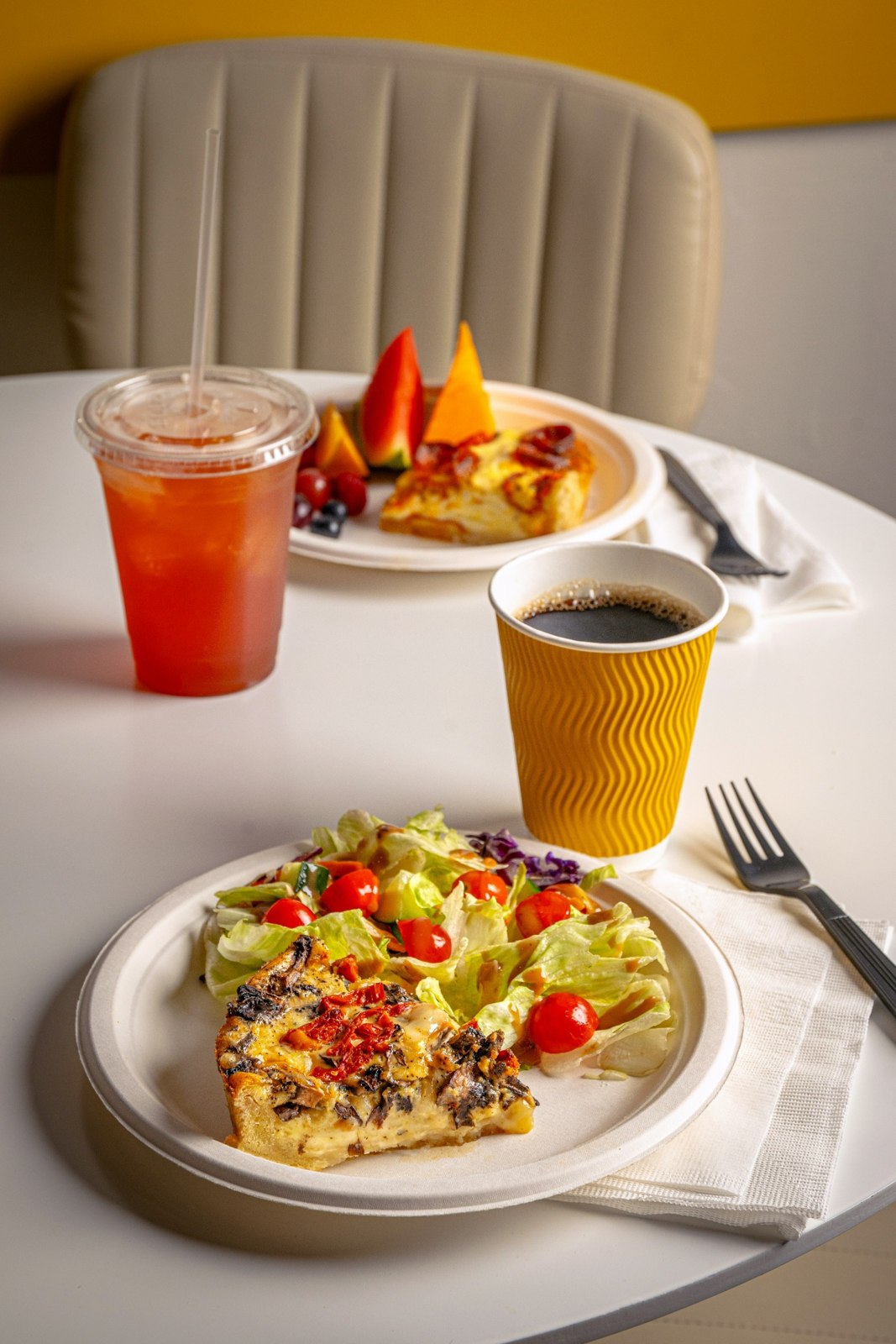 Quiche, fresh salad, coffee and an iced drink on a café table